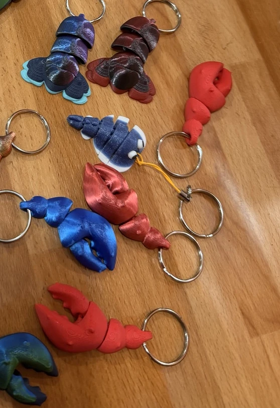 Porte-clés articulés rouges, bleus et irisés, photographiés sur une table en bois